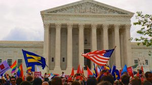 A crowd in front of the Supreme Court holds up LGBT pride and marriage equality flags