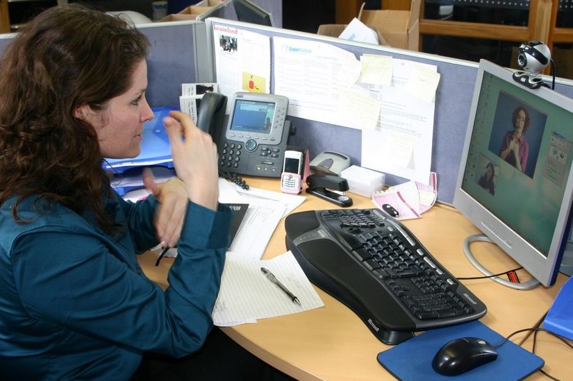 Photograph of a Deaf woman using a Video Relay Service to communicate with a hearing person.